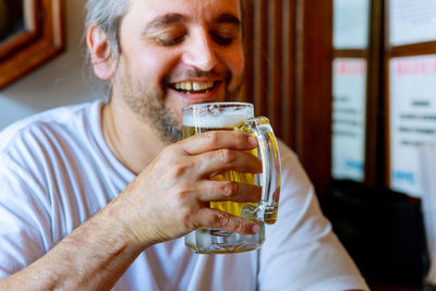 Smiling man drinking beer at home