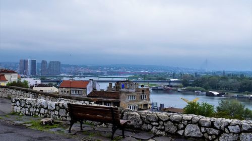 Buildings by river against sky in city