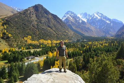 Man standing on rock by mountains against sky