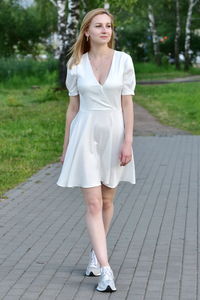 Portrait of young woman standing on footpath