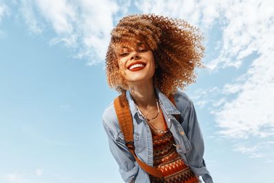 Portrait of young woman standing against sky