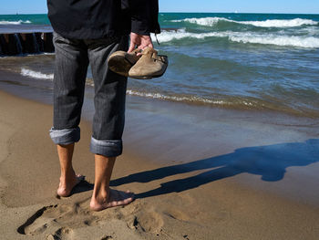 Low section of man standing on beach