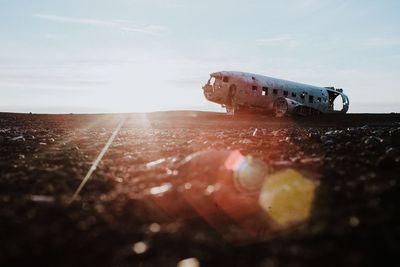 Abandoned airplane on field against sky during sunny day