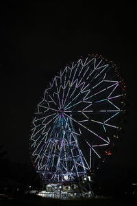 Low angle view of illuminated ferris wheel against sky at night