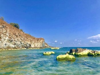 Scenic view of rocks in sea against blue sky