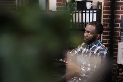 Side view of young man looking through window