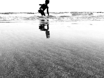 Low section of man walking on beach