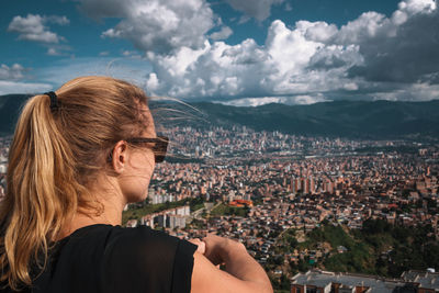 Rear view of woman looking at city buildings against sky