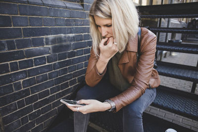 Young woman using mobile phone while sitting on steps