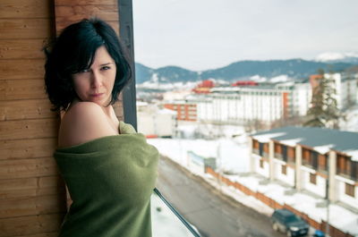 Portrait of topless woman with blanket standing in balcony