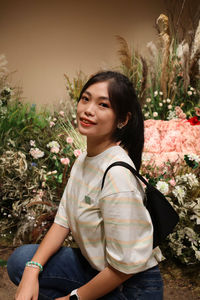 Portrait of smiling young woman against plants