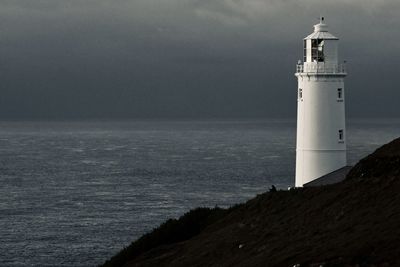 Lighthouse by sea against sky