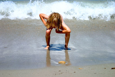 Boy bending on shore at beach