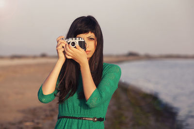 Portrait of young woman standing against sky