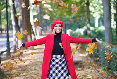 Portrait of young woman standing against trees