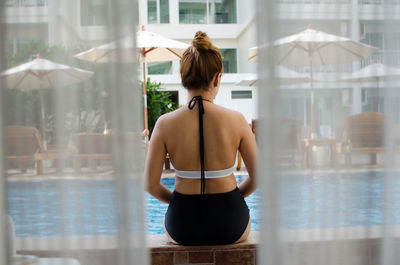 Rear view of woman sitting on retaining wall