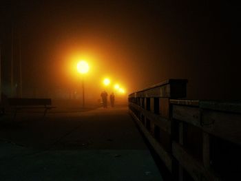 Man on illuminated road against sky during sunset