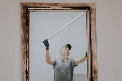 A man working with a crowbar in a doorway.