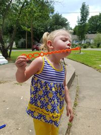 Cute girl blowing on bubble wand in park