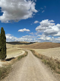 Road amidst field against sky