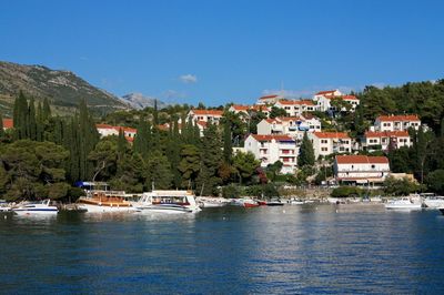 Scenic view of river by buildings against blue sky