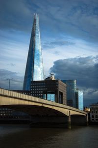 Low angle view of bridge over river against cloudy sky