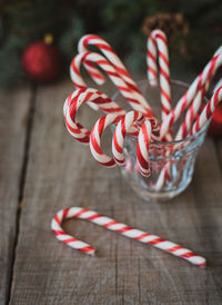 Close up of a cup full of candy canes against christmas backdrop.