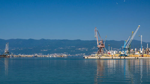 Commercial dock by sea against blue sky