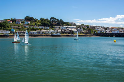 Sailboats in sea against buildings in city