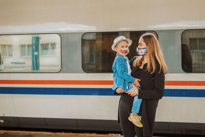 Mother looking while holding son at railroad station against train