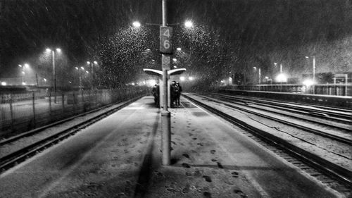 Illuminated railroad tracks against sky at night during winter