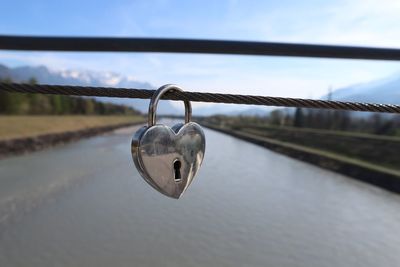 Close-up of padlocks on railing against bridge