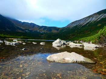 Scenic view of lake by mountains against sky