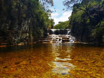 Scenic view of waterfall in forest against sky