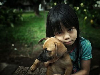 Close-up portrait of girl with dog sitting in park