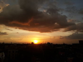 View of cityscape against cloudy sky at sunset