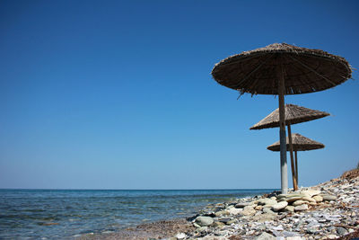 Traditional windmill on beach against clear sky