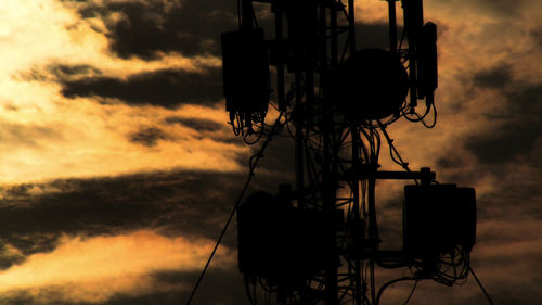 Low angle view of silhouette telephone against sky during sunset