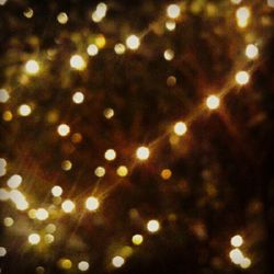 Defocused image of illuminated lights against sky at night