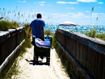 Rear view of man pulling luggage at beach