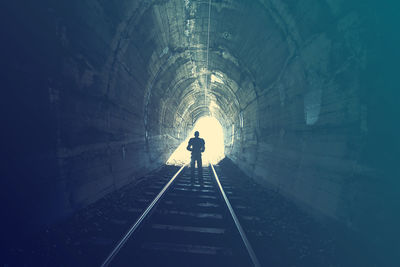 Rear view of silhouette man walking in tunnel
