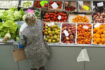 High angle view of woman buying vegetables at market stall