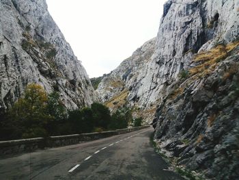 Road amidst rocky mountains against sky
