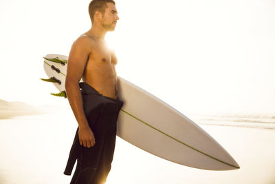 Young man standing on beach against sky