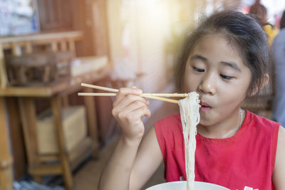 Cute girl eating noodles at restaurant