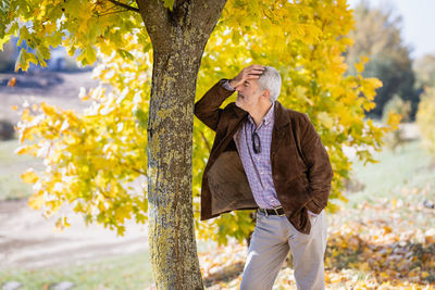 Young woman standing against tree