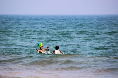 Friends plying with ball in sea