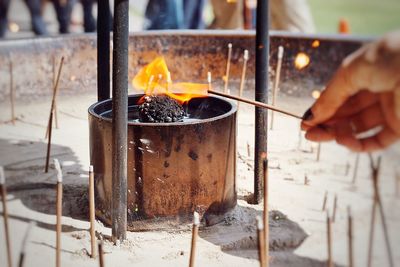 Close-up of human hand lighting incense stick from fire