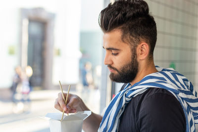 Portrait of young man holding camera outdoors