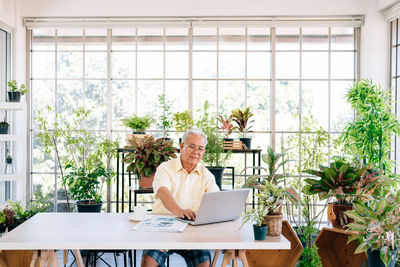 Senior man using laptop at greenhouse